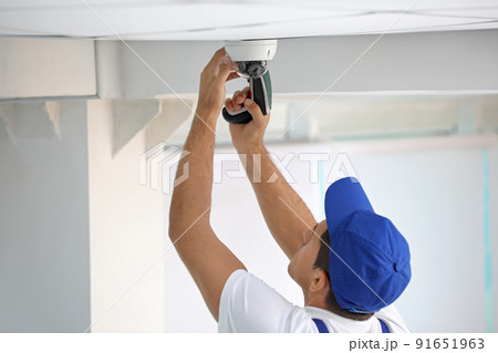 Technician installing CCTV camera on ceiling indoors Technician installing CCTV camera on ceiling indoors 91651963