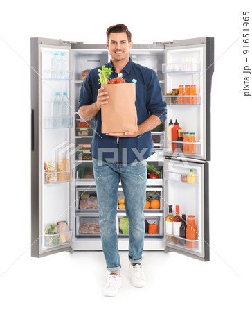 Man with bag of groceries near open refrigerator on white background Man with bag of groceries near open refrigerator on white background 91651965