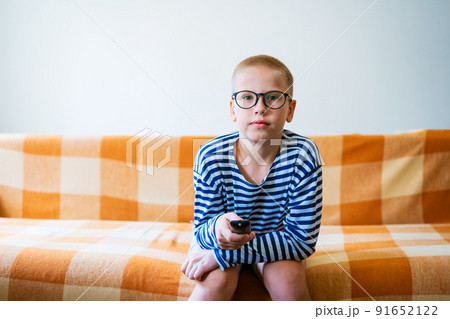 A teenage boy watches tv, using remote control to change channels. Young man A teenage boy watches tv, using remote control to change channels. Young man 91652122