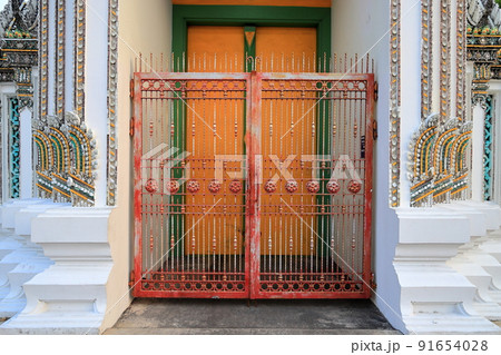 Beautiful detail of traditional Thai art at Ancient Temple gate, decorated made from metal and ceramic tile on the building wall of public Buddhist temple ,textures background Beautiful detail of traditional Thai art at Ancient Temple gate, decorated made from metal and ceramic tile on the building wall of public Buddhist temple ,textures background 91654028