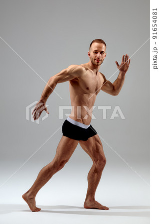 Young male athlete posing. Handsome athletic male power guy. Fitness muscular person. Young athlete showing muscles in the studio, posing shirtless on gray background. Young male athlete posing. Handsome athletic male power guy. Fitness muscular person. Young athlete showing muscles in the studio, posing shirtless on gray background. 91654081