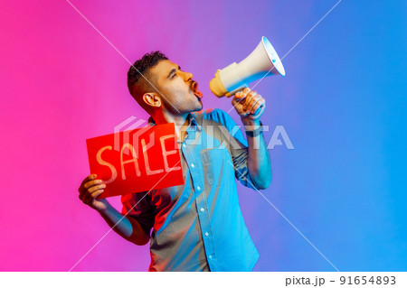 Portrait of smiling happy man in shirt paying attention announcing big sale yelling at loudspeaker, black Friday shopping. Indoor studio shot isolated on colorful neon light background. Portrait of smiling happy man in shirt paying attention announcing big sale yelling at loudspeaker, black Friday shopping. Indoor studio shot isolated on colorful neon light background. 91654893