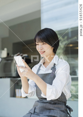 カフェ スマートフォンを使う女性スタッフ 91655426