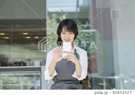 カフェ スマートフォンを使う女性スタッフ 91655427
