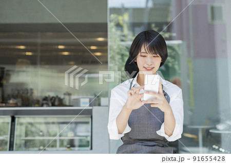 カフェ スマートフォンを使う女性スタッフ 91655428