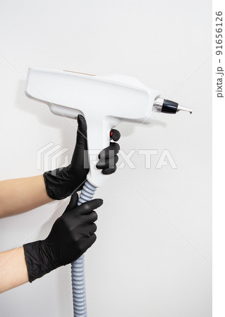 The master of laser hair removal holds a laser hair removal machine in his hands. Removal of hair on all parts of the body. Hair removal machine. The master of laser hair removal holds a laser hair removal machine in his hands. Removal of hair on all parts of the body. Hair removal machine. 91656126