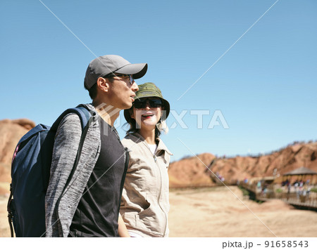 asian couple tourists backpackers walking chatting in national geological park, side view 91658543