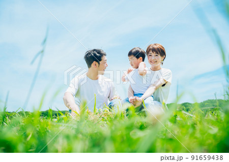 晴天の緑地に座る親子 91659438
