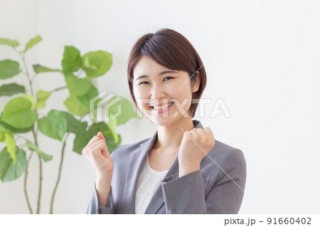 ガッツポーズをするスーツを着た若い女性 91660402