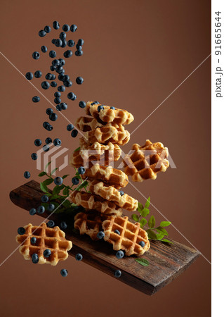Waffles with fresh blueberries in motion. Waffles with fresh blueberries in motion. 91665644