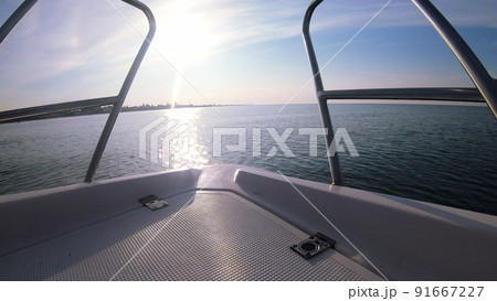 Seascape, view of sea waves with sun reflection from prow of motorboat. Boat jumping on waves on sunny summer day. Yacht motor boat sailing fast at sea horizon. Extreme sport entertainment background Seascape, view of sea waves with sun reflection from prow of motorboat. Boat jumping on waves on sunny summer day. Yacht motor boat sailing fast at sea horizon. Extreme sport entertainment background 91667227