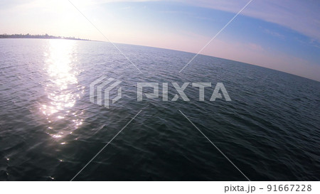 View coastline with houses and hotels from motor boat in sea while moving along sea waves Sun glare reflected on sea surface. Yacht motor boat sailing fast at sea Natural tourism traveling background 91667228