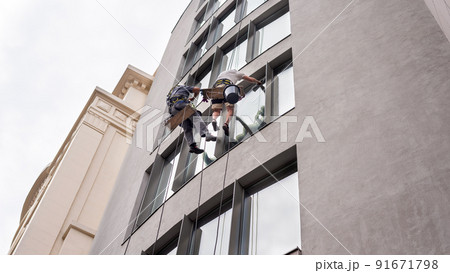 Two workers washing windows outside a building 91671798