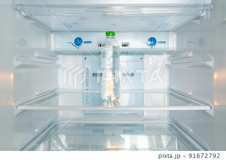 A cold bottle of clean drinking water in a white refrigerator 91672792