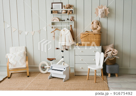 Cozy interior of a children's room, a play area. Toys, a bicycle, a piano, a chest of drawers and clothes on a hanger. Scandinavian apartment style 91675492
