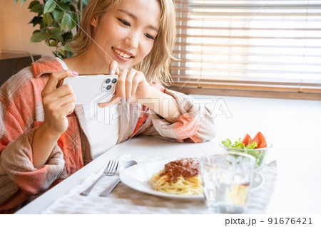 スマホで食事の写真を撮る若い女性 91676421