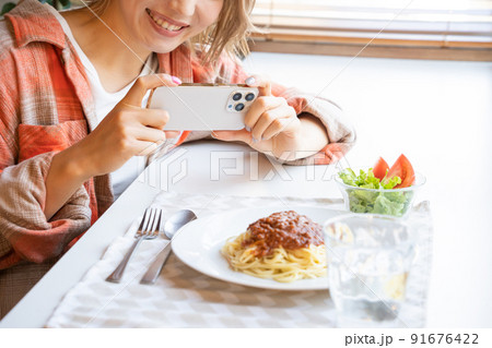 スマホで食事の写真を撮る若い女性 91676422