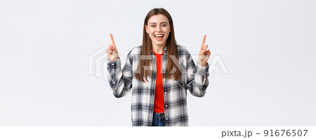 Lifestyle, different emotions, leisure activities concept. Happy beautiful girl in checked shirt, pointing fingers up and laughing carefree, showing good summer vacation ideas, promo or banner Lifestyle, different emotions, leisure activities concept. Happy beautiful girl in checked shirt, pointing fingers up and laughing carefree, showing good summer vacation ideas, promo or banner 91676507