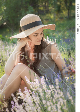 The girl in the hat sit in the middle of a lavender field 91677381
