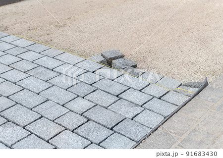 Construcion site of pavement granite cobblestone road in old city center installation or renovation repair. Roadworks stonework at pedestrian area. Paved sidewalk reconstruction. Urban development 91683430