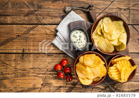 Variety of Potato chips - Crinkle, homemade, hot BBQ. Wooden background. Top view. Copy space 91683579