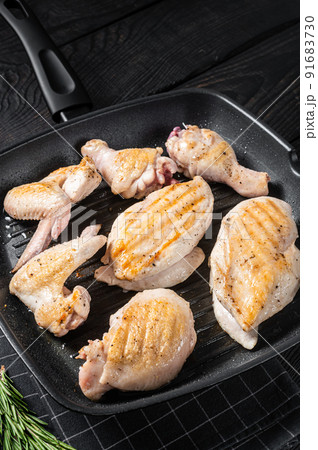 Roasted on a grill skillet chicken meat and chicken parts - drumstick, breast fillet, wing, thigh. Black wooden background. Top view Roasted on a grill skillet chicken meat and chicken parts - drumstick, breast fillet, wing, thigh. Black wooden background. Top view 91683730