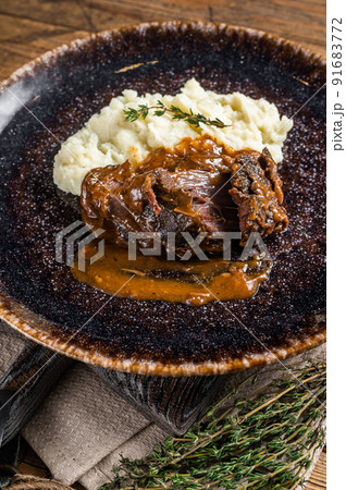 Beef cheeks stewed in red wine sauce with mashed potatoes. Wooden background. Top view Beef cheeks stewed in red wine sauce with mashed potatoes. Wooden background. Top view 91683772