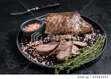 Barbecue dry aged wagyu Tri Tip beef steak on a plate with pink salt. Black background. Top view 91683954