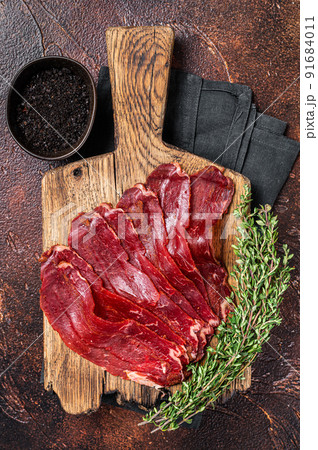 Turkish pastrami (kayseri pastirma), dried beef meat with spices. Dark background. Top view Turkish pastrami (kayseri pastirma), dried beef meat with spices. Dark background. Top view 91684011