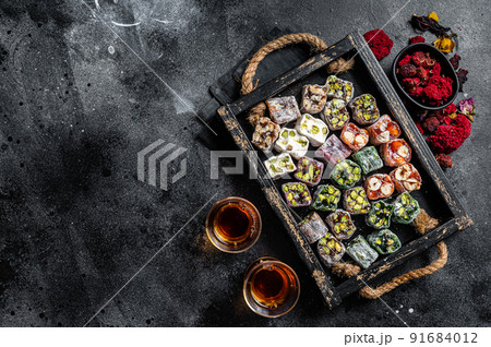 Turkish Delight Lukum, Oriental sweets with nuts and black tea. Black background. Top view. Copy space Turkish Delight Lukum, Oriental sweets with nuts and black tea. Black background. Top view. Copy space 91684012
