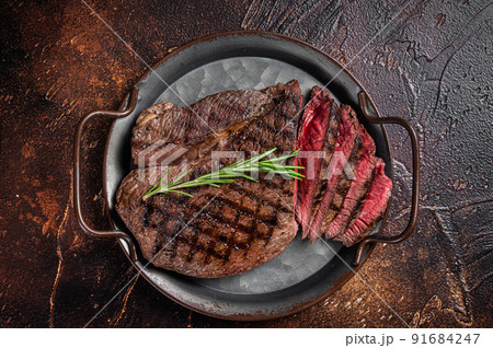 Grilled Medium Rare top sirloin beef steak or rump steak on a steel tray. Dark background. Top view Grilled Medium Rare top sirloin beef steak or rump steak on a steel tray. Dark background. Top view 91684247