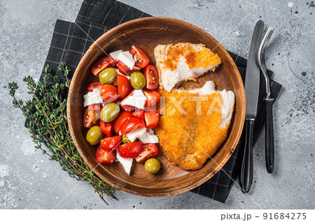 Fried tilapia fillet on a plate with salad. Gray background. Top view Fried tilapia fillet on a plate with salad. Gray background. Top view 91684275