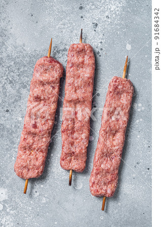 Raw Turkish Adana shish kebab on butcher table. Gray background. top view Raw Turkish Adana shish kebab on butcher table. Gray background. top view 91684342