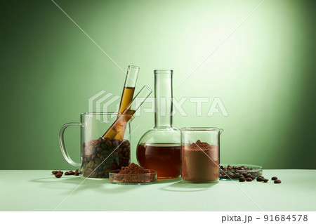 Front view of coffee decorated in transparent podium and glassware laboratory equipment green background 91684578