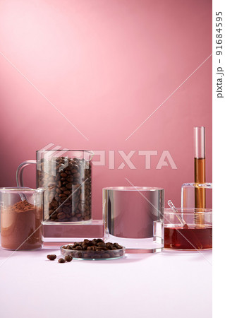 Front view of coffee decorated in transparent podium and glassware laboratory equipment pink background 91684595