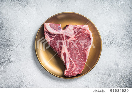 Raw T-bone porterhouse beef meat Steak on golden metalic plate. Gray background. Top view 91684620