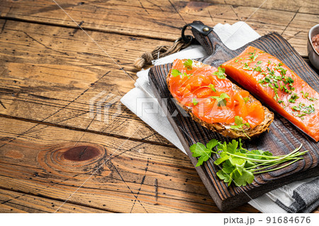 Sandwich toast with Salted salmon fillet, herbs on a wooden board. Wooden background. Top view. Copy space 91684676