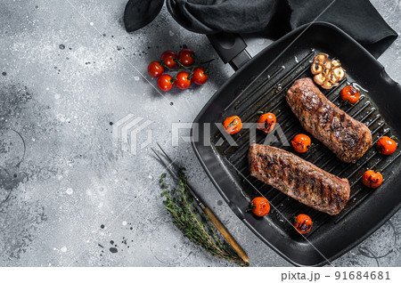 Roasted Lamb tenderloin fillet meat on grill pan, mutton sirloin steak. Gray background. Top view. Copy space 91684681