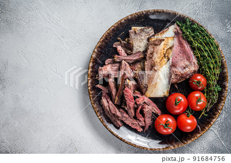 Smoked beef short ribs in rustic plate with herbs. Gray background. Top view. Copy space 91684756