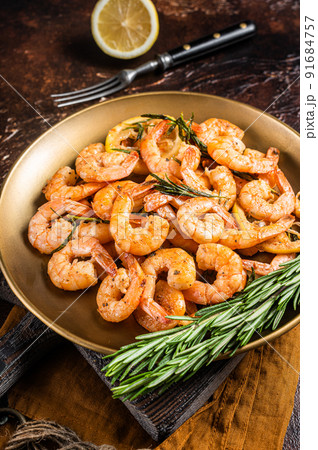 Spicy garlic chilli Prawns Shrimps with lemon and rosemary on a plate. Dark background. Top view Spicy garlic chilli Prawns Shrimps with lemon and rosemary on a plate. Dark background. Top view 91684757