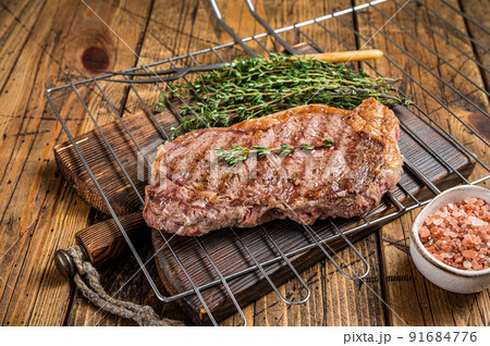 Grilled striploin or New York beef meat steak cooked on BBQ. Wooden background. Top view 91684776