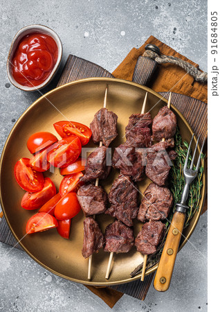 Lamb shish kebab grilled Skewers in a plate with tomato. Gray background. Top view 91684805