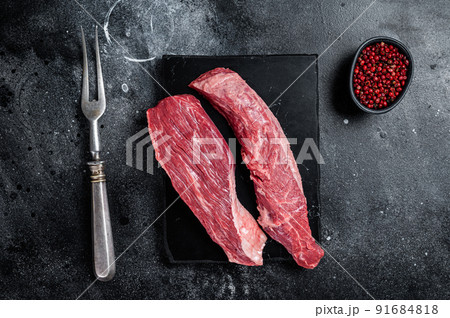 Bavette raw beef meat steak or Sirloin flap on marble board. Black background. Top view Bavette raw beef meat steak or Sirloin flap on marble board. Black background. Top view 91684818