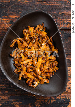 Fried forest chanterelle mushrooms with herbs. Wooden background. Top view 91685381