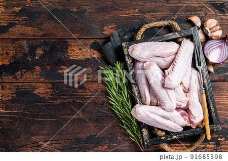Fresh Raw duck and chicken wings in a tray. Dark wooden background. Top view. Copy space 91685398