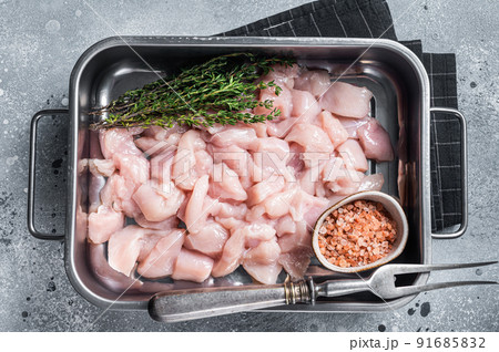 Diced raw chicken breast fillets in steel tray. Gray background. Top view Diced raw chicken breast fillets in steel tray. Gray background. Top view 91685832