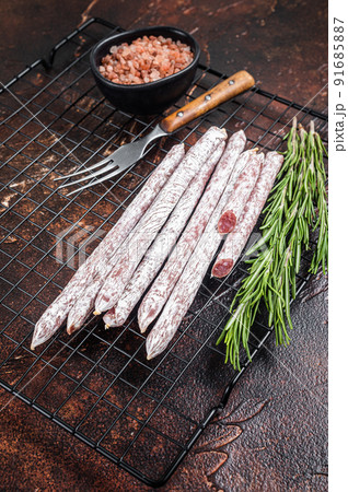 Fuet Catalan dry sausages with rosemary. Dark background. Top view Fuet Catalan dry sausages with rosemary. Dark background. Top view 91685887