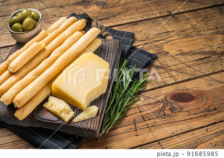 Traditional italian appetizer grissini bread sticks on wooden board with olives and parmesan cheese. Wooden bakground. Top view. Copy space 91685985