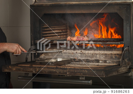 Chef makes beef steak on open fire in restaurant Chef makes beef steak on open fire in restaurant 91686263