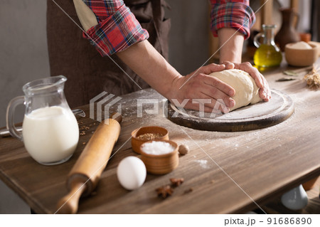 Baker man making dough and bakery ingredients for homemade bread cooking at table Baker man making dough and bakery ingredients for homemade bread cooking at table 91686890